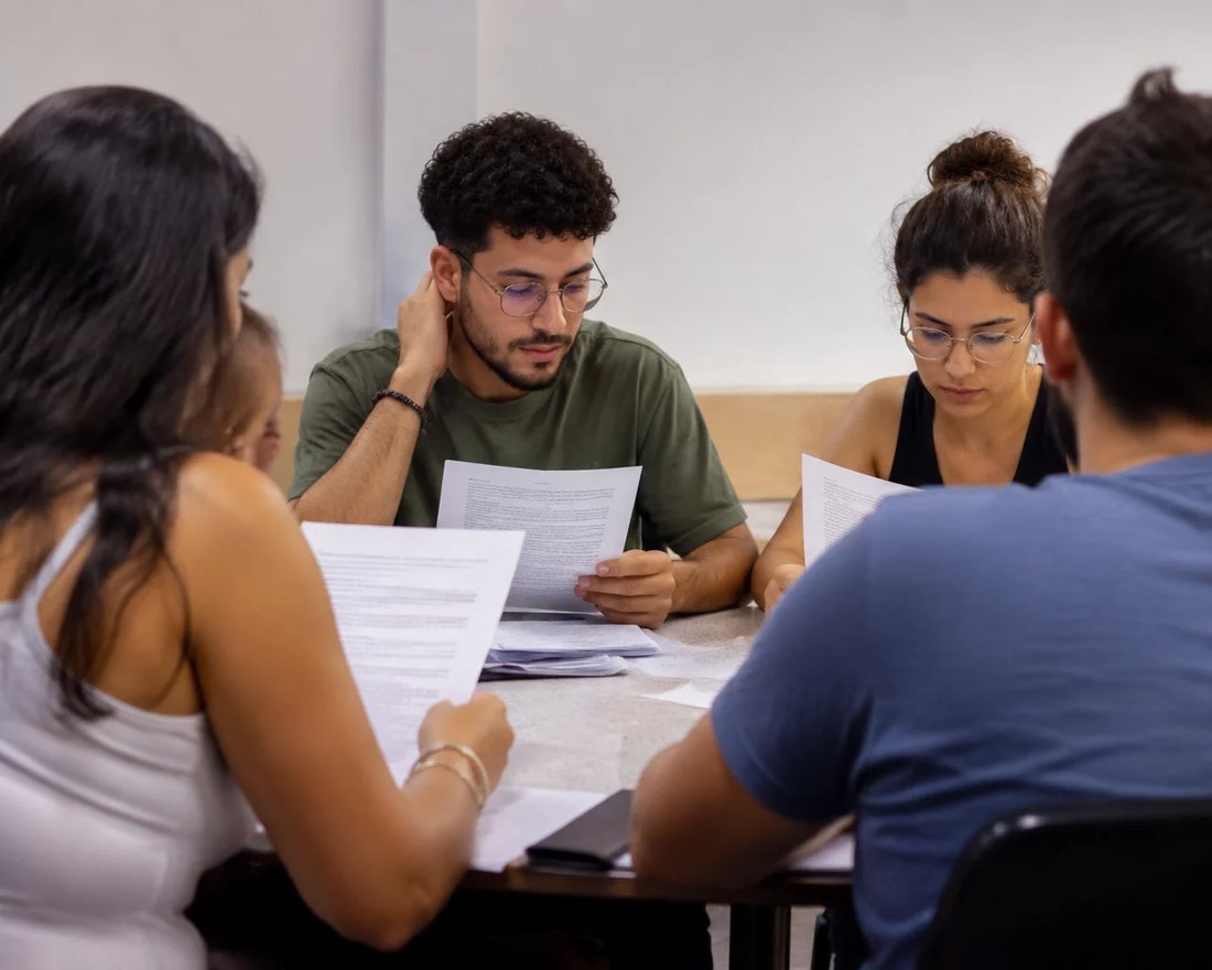 Profissionais reunidos numa sala clara enquanto uma pessoa em pé defende um ponto
